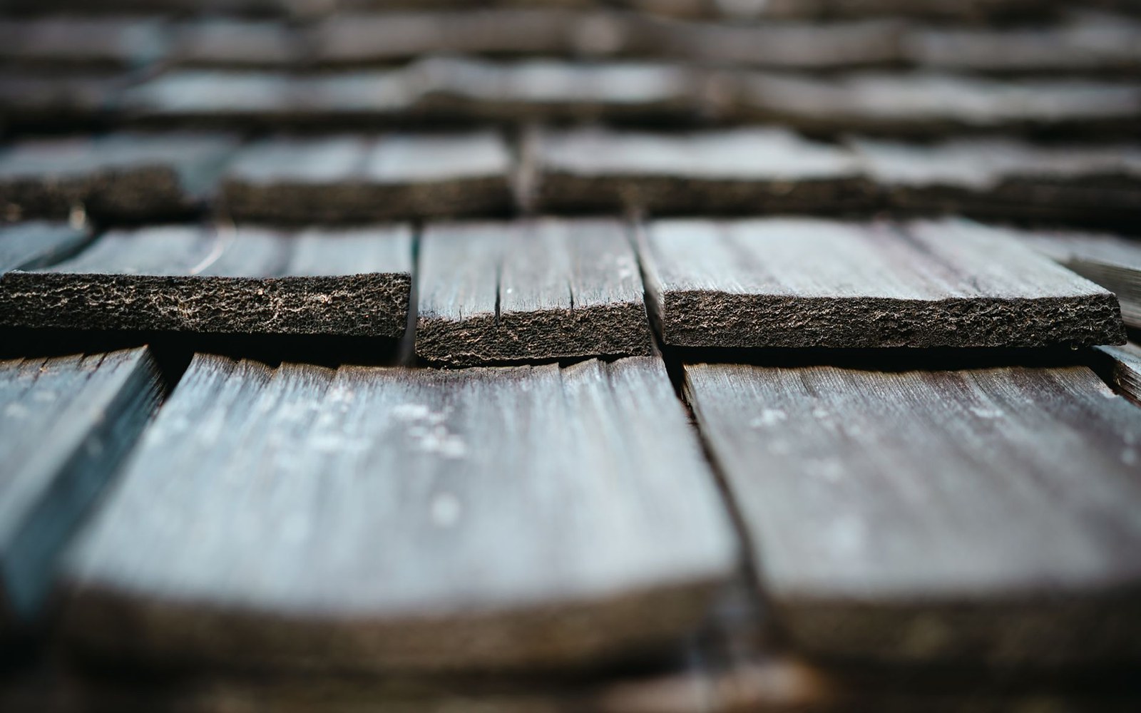 Close-up of weathered wood shingles overlapping in rows on a roof