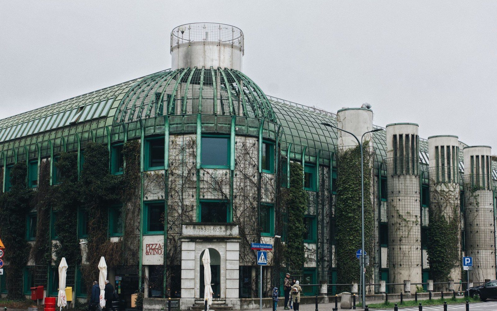 Curved glass and metal building with vine-covered walls and rounded turrets